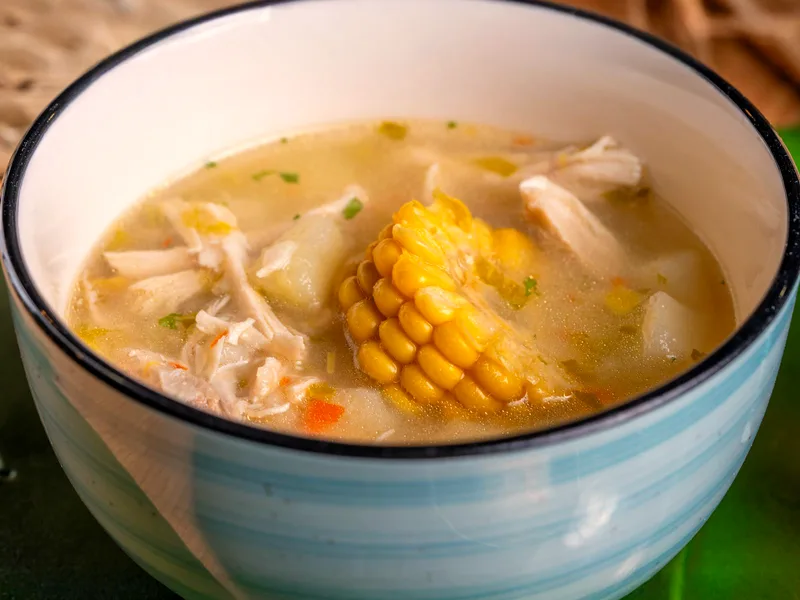 Low-carb chicken and corn soup with shredded chicken, zucchini and fresh herbs