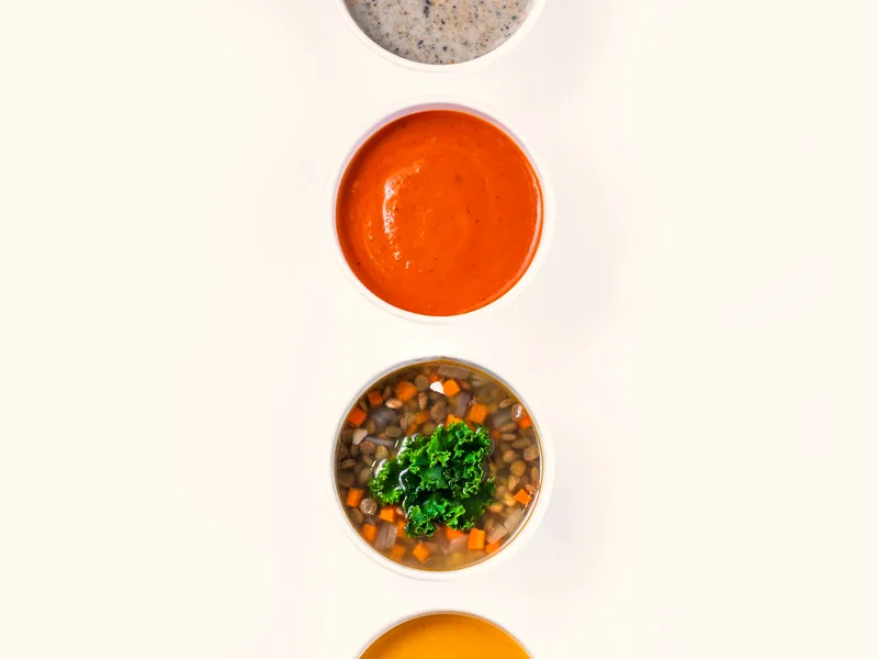 Homemade vegetable soup for canning with carrots, potatoes and jars of preserved soup